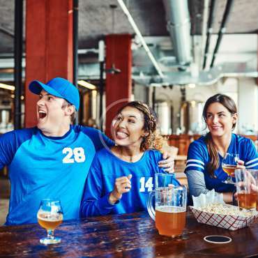 Shot of a group of friends having beers while watching a sports game at a bar